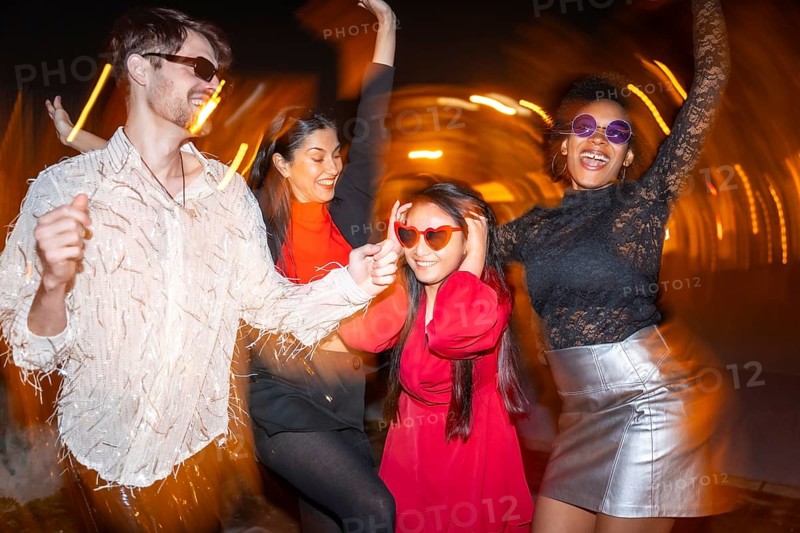 Night photo with flash and motion of four multi-ethnic friends partying in the street
