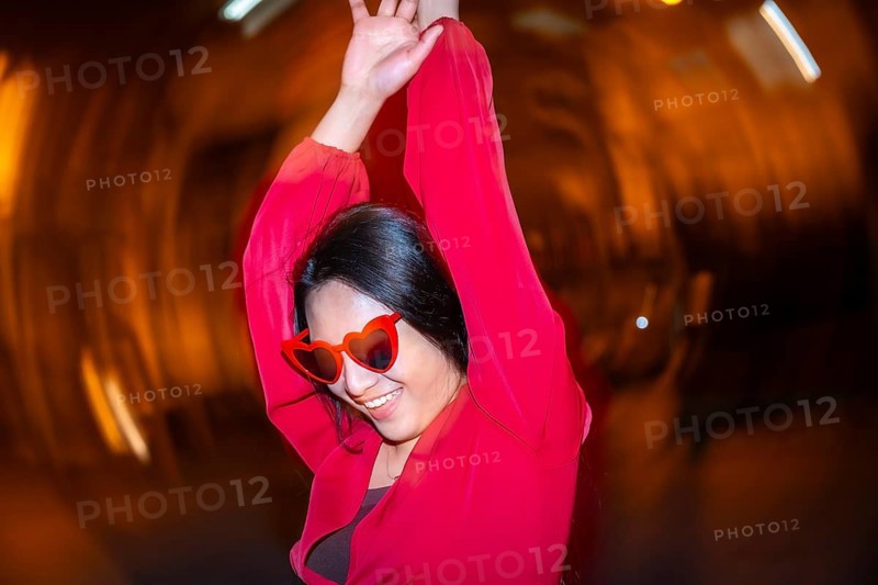 Night photo with flash and motion of fashionable woman with heart shape sunglasses dancing in the street at night