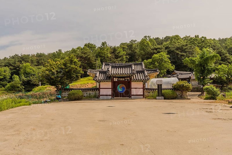 Daejeon, South Korea, May 22, 2018: Korean woman sitting under tree in front of stone wall attached to gate of Korean style building, Asia