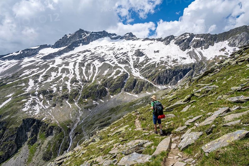 Mountaineer on rocky hiking trail, Berliner Hoehenweg, mountain landscape with snow-covered peak Gefrorene-Wand-Spitze, Zillertal Alps, Tyrol, Austria, Europe