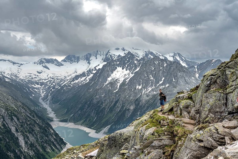Mountaineer on hiking trail, view of Schlegeisspeicher, glaciated rocky mountain peaks Hoher Weisszint and Hochfeiler with glacier Schlegeiskees, Berliner Hoehenweg, Zillertal Alps, Tyrol, Austria, Europe