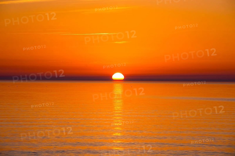 Intense, atmospheric sunset with bright orange-yellow sky over the Baltic Sea, reflection of the light in the calm water, Hiddensee Island, Mecklenburg-Western Pomerania, Germany, Europe