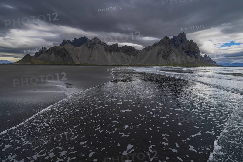 Vestrahorn, mountains with black lava sand, reflection in the water, south coast of Iceland