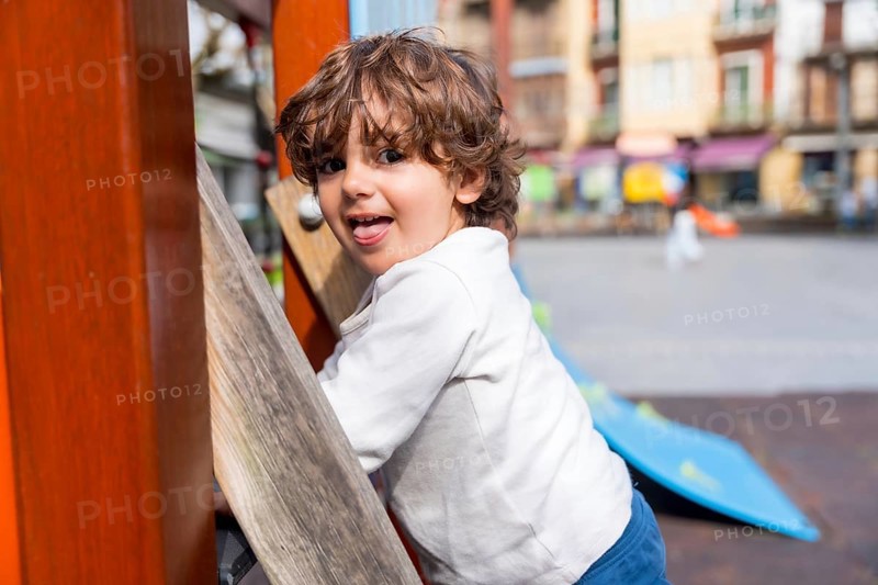 Close-up of a happy girl looking at camera before going up a slide in a playground