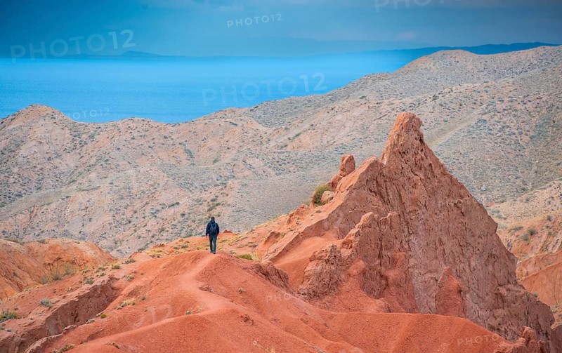 Hiker in front of eroded mountain landscape, sandstone cliffs, canyon with red and orange rock formations, Konorchek Canyon, Chuy, Kyrgyzstan, Asia