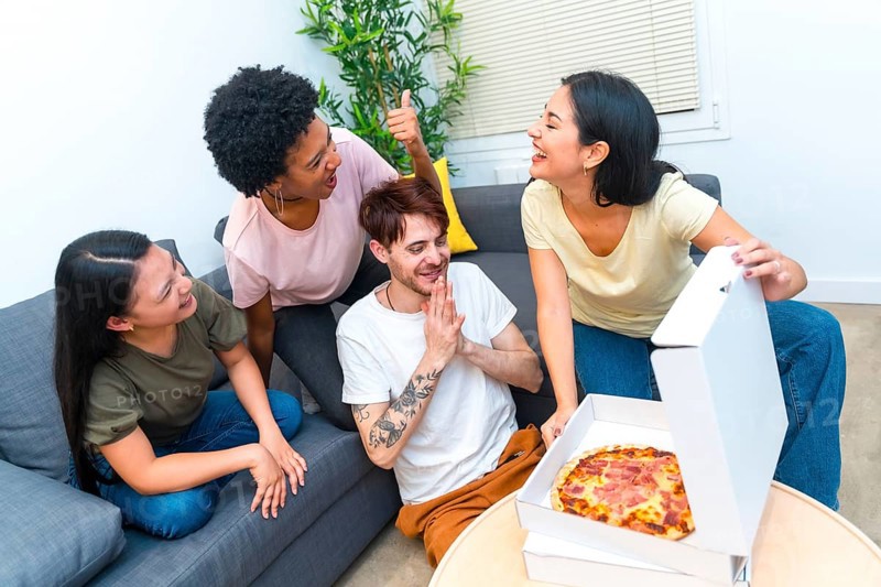 Top view of a group of multi-ethnic hungry friends opening a delivered pizza box