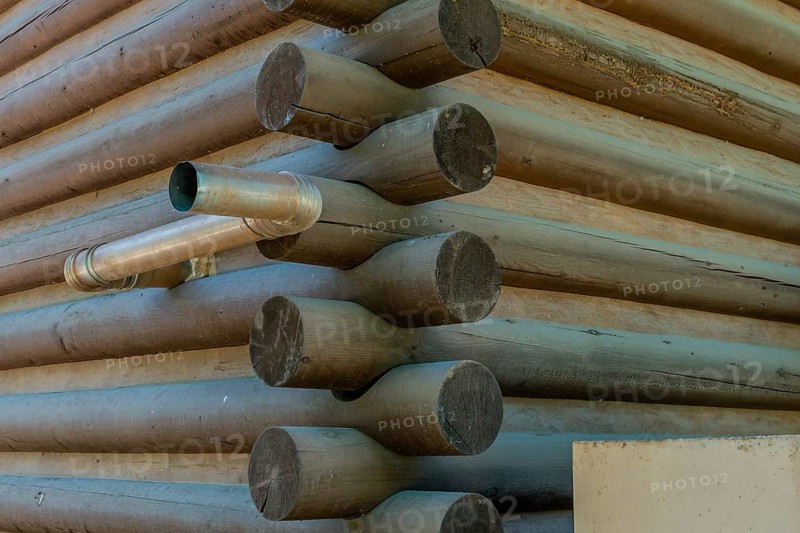 Metal exhaust pipe protruding from side exterior wall of wood log building