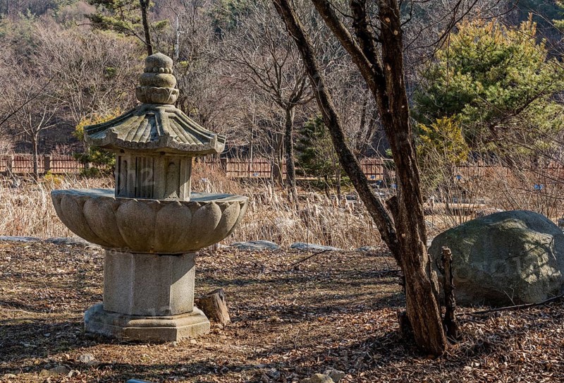 Stone carved pagoda in run down garden on sunny afternoon