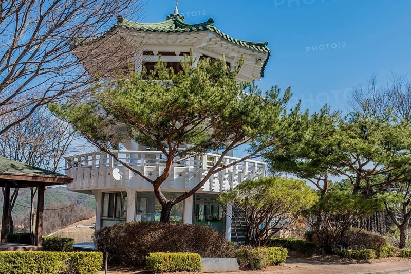 Three story white pagoda under blue sky in roadside park
