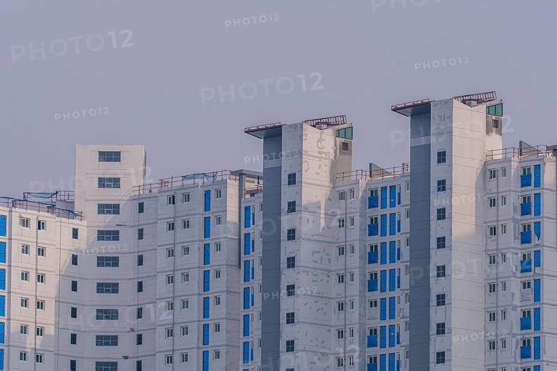 New highrise apartments with unfinished white concrete exterior walls and blue coverings on widow frames in the Shintanjin area of Daejeon, South Korea, Asia