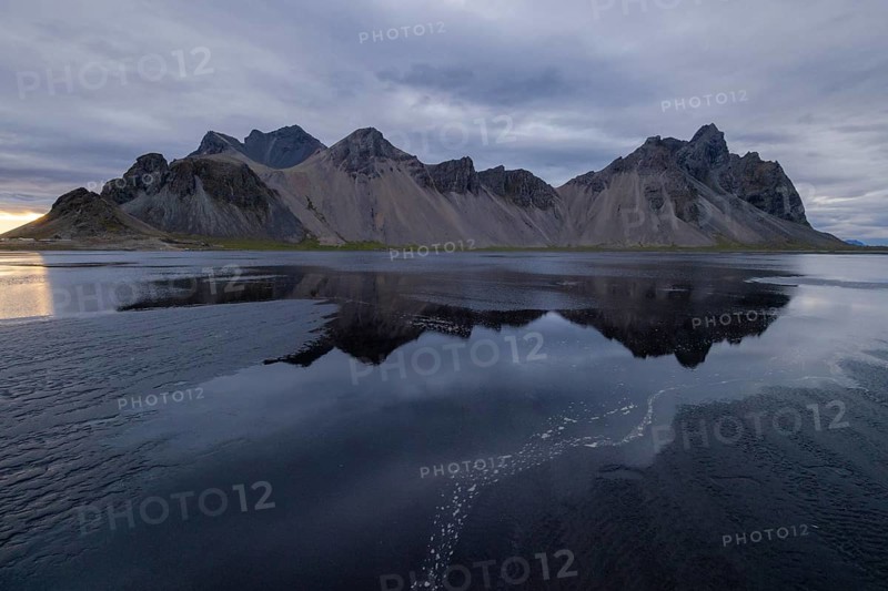 Vestrahorn, mountains with black lava sand, reflection in the water, south coast of Iceland