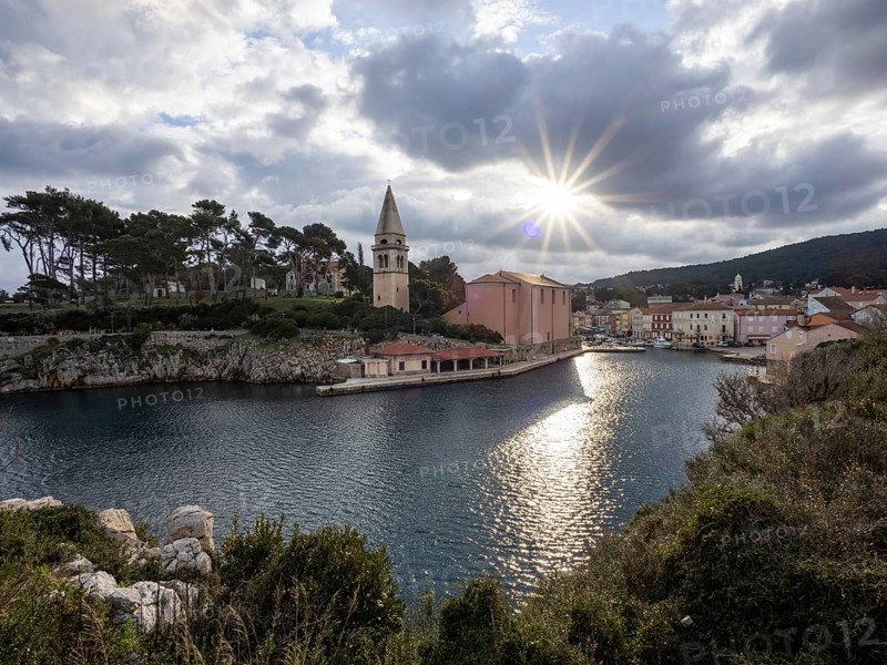 Sun breaking through clouds, view of the harbour entrance of Veli Losinj, with St. Anthony's Church, island of Losinj, Kvarner Gulf Bay, Adriatic Sea, Croatia, Europe