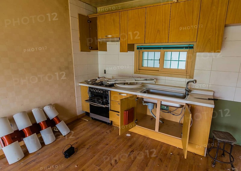Kitchen area of abandoned house with dirt and electrical fixtures debris on counter top and leaning against wall