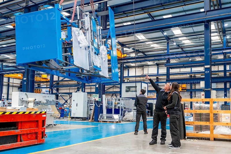 Team of engineers lifting heavy machinery using a crane inside a cnc modern logistic factory
