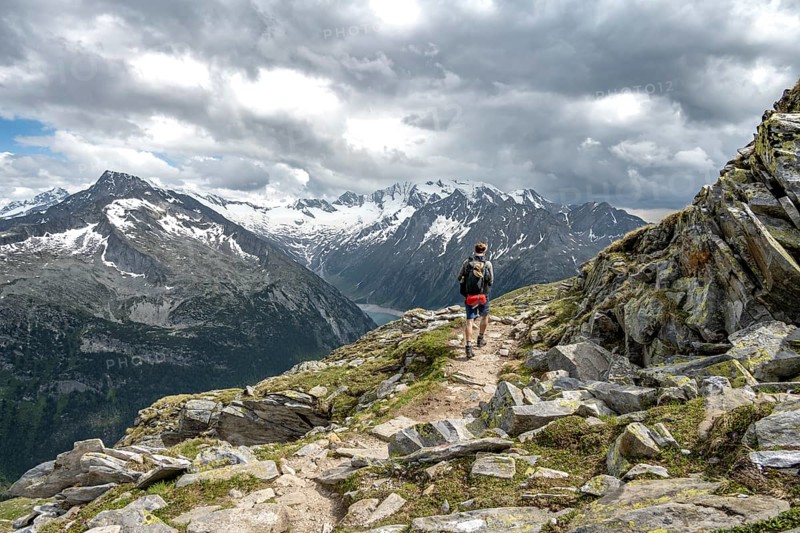 Mountaineer on hiking trail with snow, Berliner Hoehenweg, mountain landscape with glaciated peaks Hochfeiler and Hoher Weisszint, Zillertal Alps, Tyrol, Austria, Europe