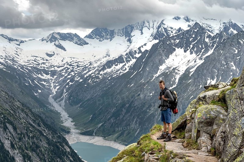 Mountaineer on hiking trail, view of Schlegeisspeicher, glaciated rocky mountain peaks Hoher Weisszint and Hochfeiler with glacier Schlegeiskees, Berliner Hoehenweg, Zillertal Alps, Tyrol, Austria, Europe