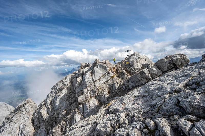 Mountaineer on the rocky summit of the Watzmann Mittelspitze with summit cross, Watzmann crossing, Berchtesgaden National Park, Berchtesgaden Alps, Bavaria, Germany, Europe