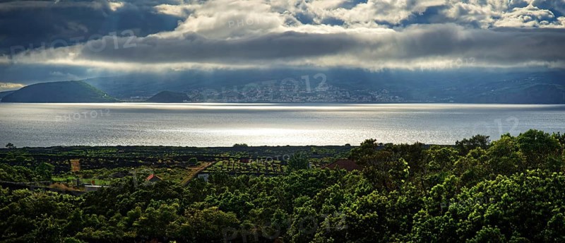 View of the island of Faial and the town of Horta with sun rays breaking through the clouds, Horta, Faial, Azores, Portugal, Europe