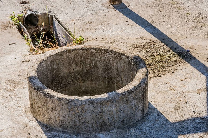 Closeup of concrete irrigation well and drainage pipe used for irrigation of crops in rural community
