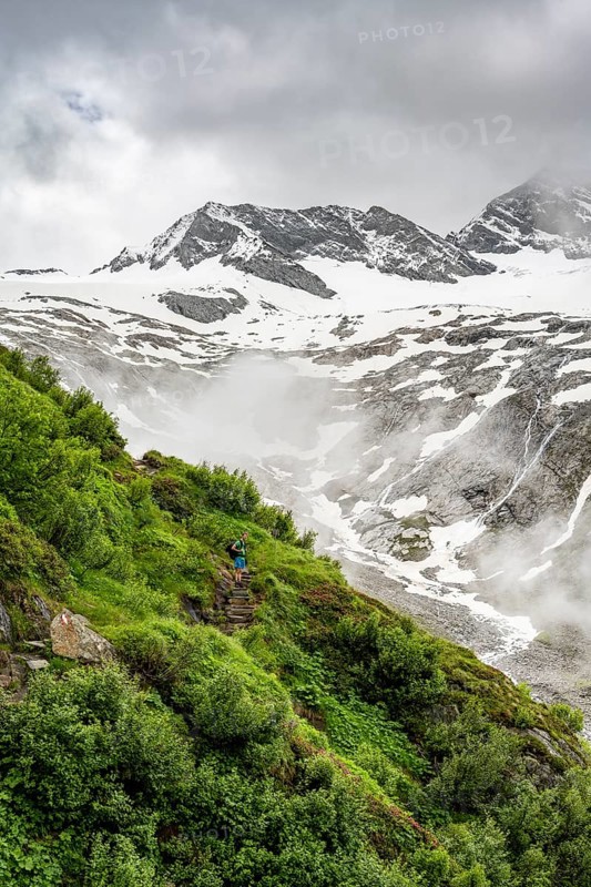 Mountaineers on a hiking trail, in the background glaciated peak Dosso Largo and glacier Schlegeiskees, cloudy atmospheric mountain landscape, ascent to Furtschaglhaus, Berliner Hoehenweg, Zillertal, Tyrol, Austria, Europe
