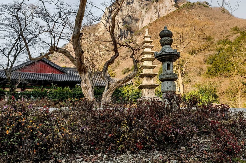Stone carved lantern and nine story pagoda in Buddhist temple with mountain in background
