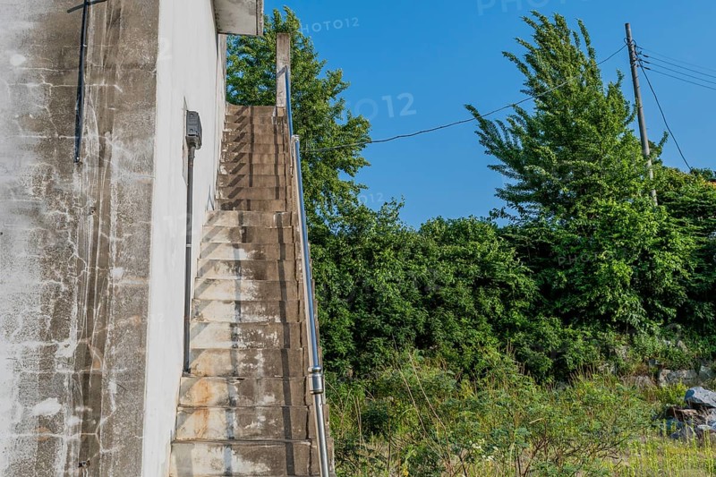 Outside staircase going up to roof of white field in field under blue sky