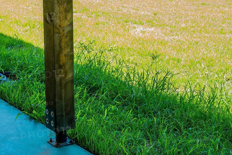 Square wooden support column attached to concrete base using metal anchor plate