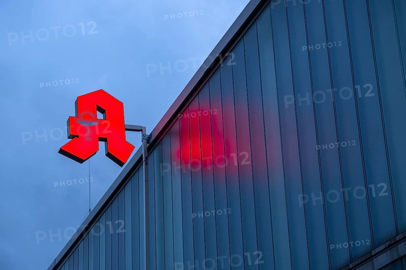 Illuminated pharmacy sign in front of a stormy sky on a facade in Duesseldorf, Germany, Europe