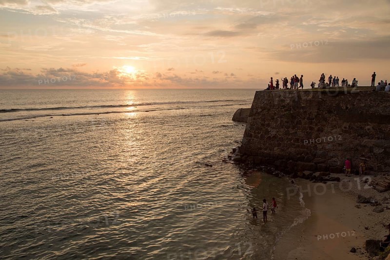 Tourists walk on fort ramparts at sunset in historic town of Galle, Sri Lanka, Asia