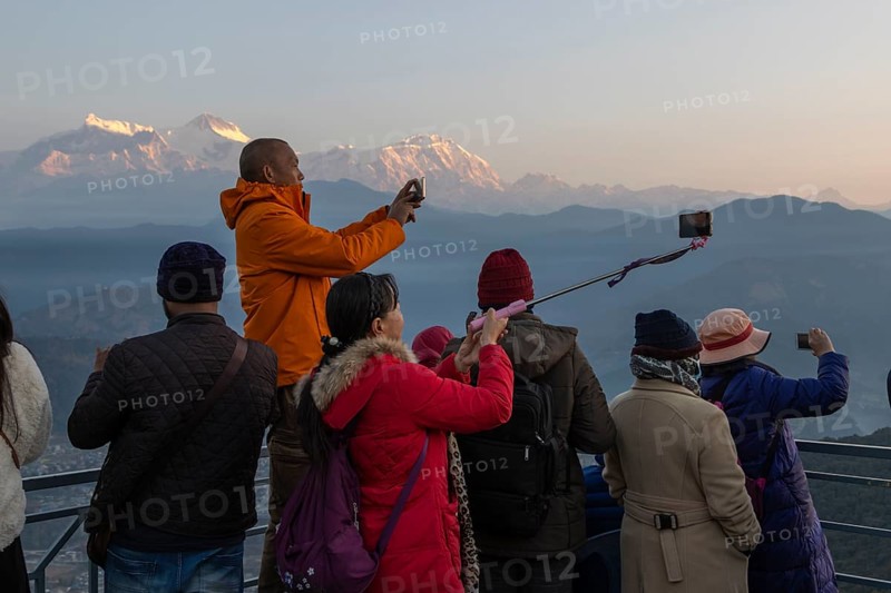 Asian-looking tourists watching and photographing sunrise as well as shooting selfies on the second day of the 2024 year from Sarangkot, with mountains of the Annapurna Massif in the background. Pokhara, Kaski District, Gandaki Province, Nepal, Asia