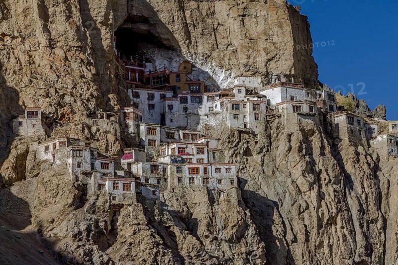 Phugtal Gompa, one of the most spectacularly located Buddhist monasteries of Ladakh, which clings to a mountain cliff, high above the valley floor. It belongs to the Gelug school of the Tibetan Buddhism. Photographed on a sunny, blue-sky day in late September, autumn. Zanskar Range of the Himalayas. Kargil District, Union Territory of Ladakh, India, Asia