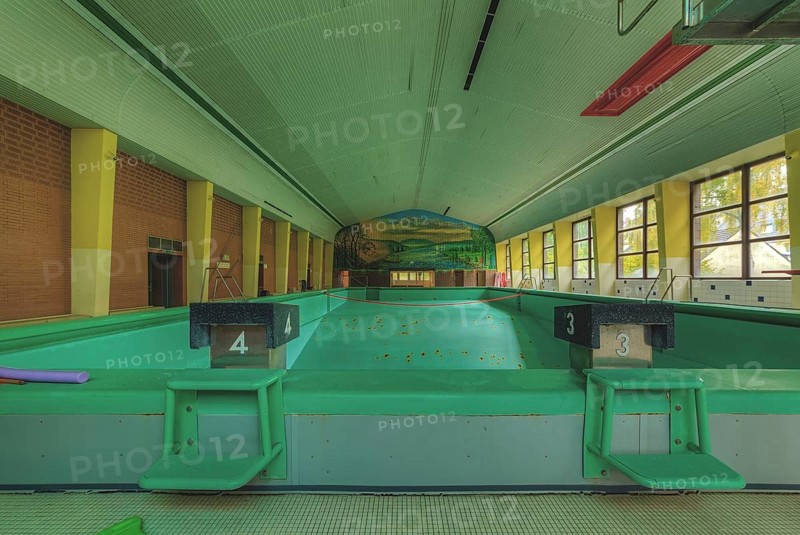 An abandoned indoor swimming pool with starting blocks and a mural in the background, Bad am Park, Lost Place, Essen, North Rhine-Westphalia, Germany, Europe