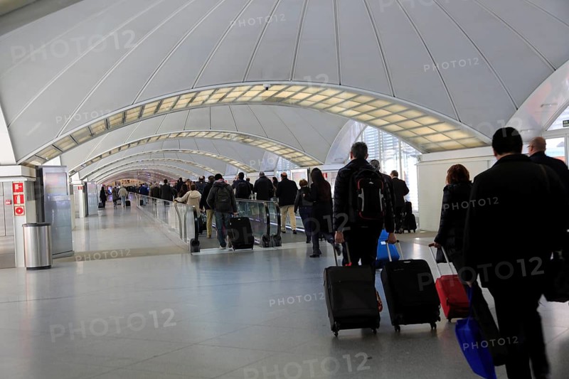 Passengers pulling luggage bags along a bright corridor, Atocha railway station, Madrid, Spain, Europe