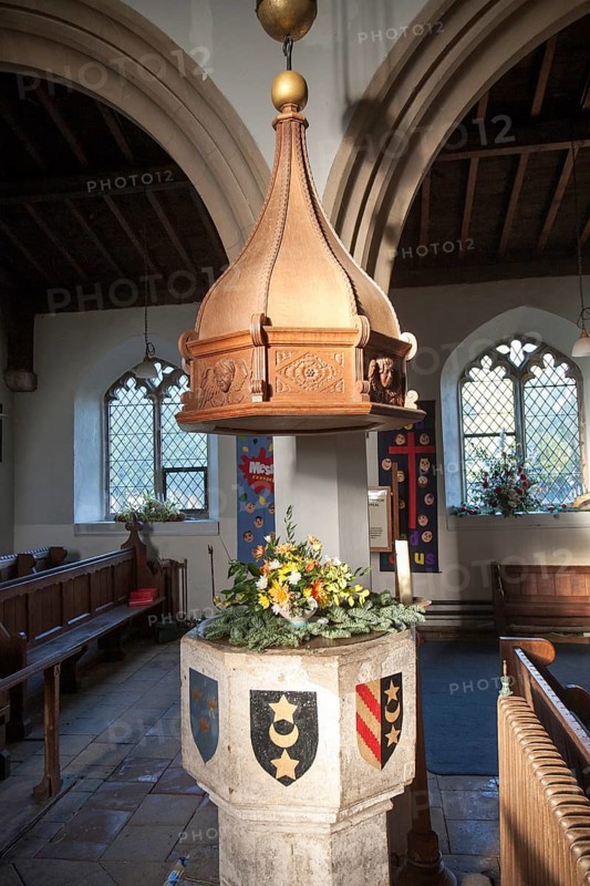 Baptismal font with heraldic shield inside church of Saint Leonard, Horringer, Suffolk, England, UK