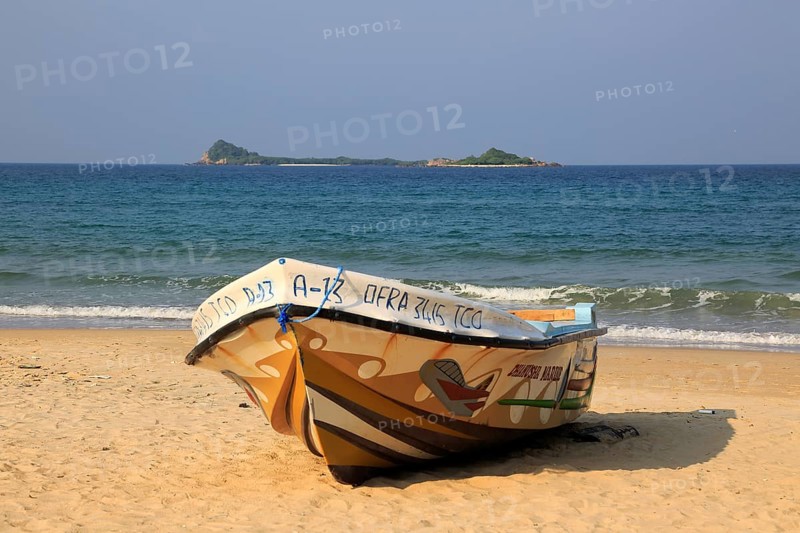 Boat on tropical beach at Nilavelli, Trincomalee, Sri Lanka, Asia with Pigeon Island in background, Asia