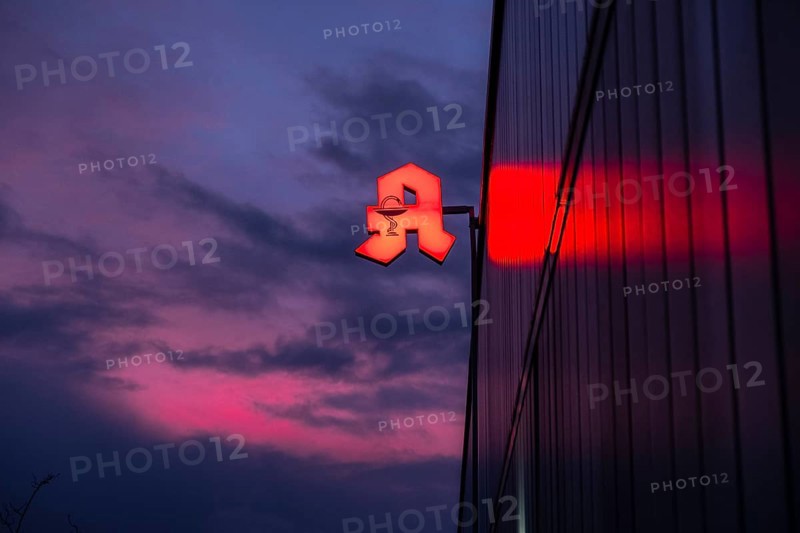 Illuminated pharmacy sign in front of a stormy sky on a facade in Duesseldorf, Germany, Europe