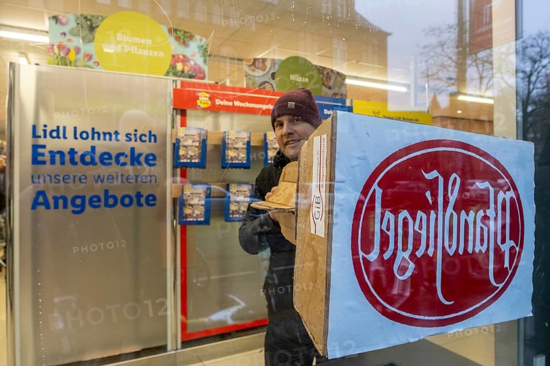 Germany, Berlin, 21.12.2023, action by Gemeingut in BuergerInnenhand (GiB), actions in front of branches of LIDL, Aldi and BMW, here a Lidl branch in Luisenstrasse / Berlin-Mitte, activists press a large deposit seal on a door of the LIDL branch, Carl Wassmuth (photo), spokesman for Gemeingut: Super-rich like LIDL owner Dieter Schwarz only pay tiny tax rates, Europe