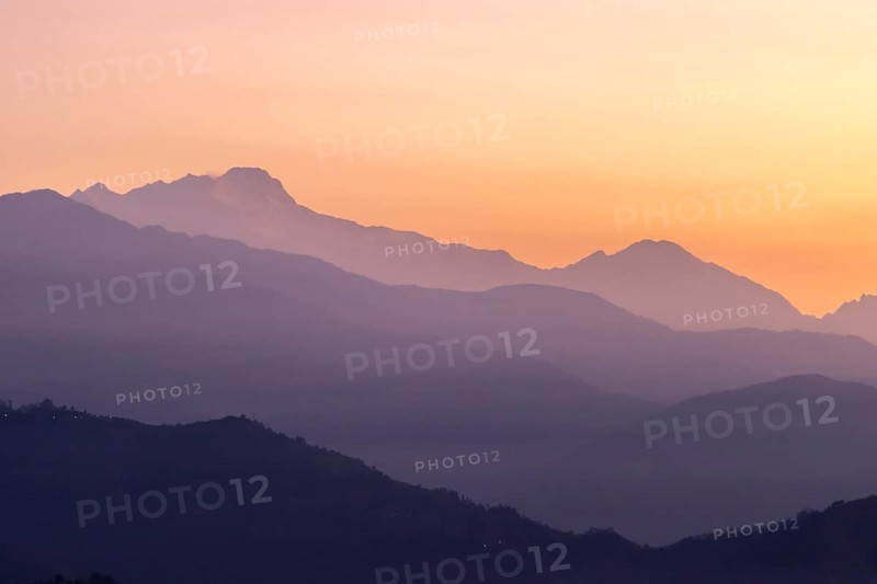 Silhouette of the Himalayan peaks, including Himalchuli and Baudha Himal, backlit by the orange sky, seen shortly before sunrise on a January, winter morning from Sarangkot, the popular viewpoint above Pokhara. Kaski District, Gandaki Province, Nepal, Asia