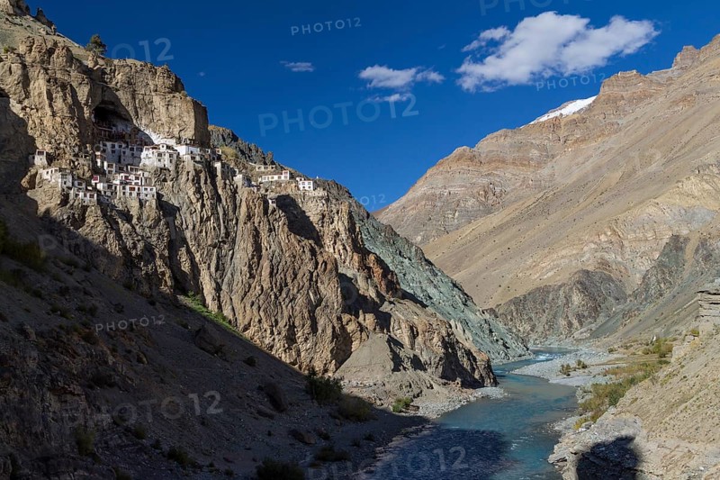 Phugtal Gompa, one of the most spectacularly located Buddhist monasteries of Ladakh, which clings to a mountain cliff, high above Tsarab Chu, the river that cuts across the Zanskar Range of the Himalayas. The monastery belongs to the Gelug school of the Tibetan Buddhism. Photographed on a sunny, blue-sky day in late September, autumn. Kargil District, Union Territory of Ladakh, India, Asia