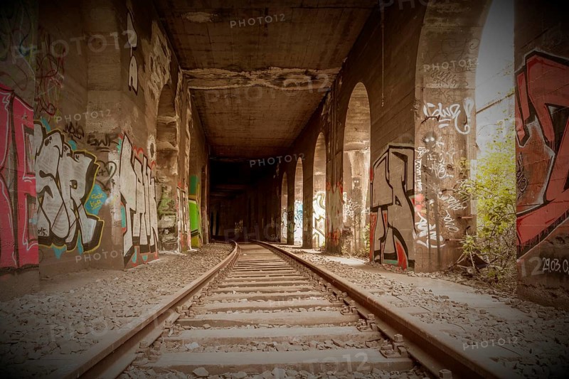 Symmetrical view through a tunnel with tracks, walls sprayed with graffiti, former railway branch Rethel, Lost Place, Flingern, Duesseldorf, North Rhine-Westphalia, Germany, Europe