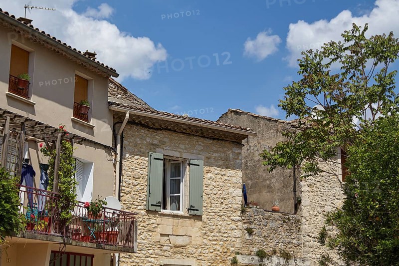 Old sandstone-walled houses with windows, shutters, balcony and a balcony in Goudargues, Gard department, Occitanie region, France, Europe