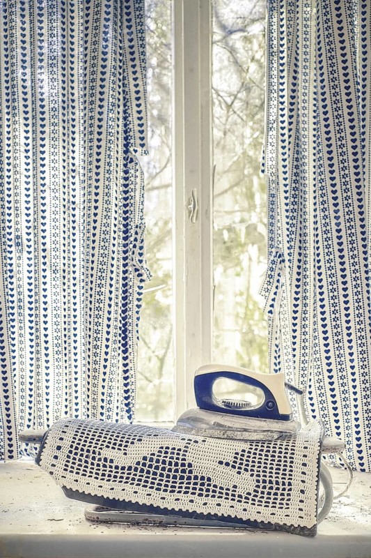 An old iron on a lace fabric in front of a window with blue curtains, urologist's villa Dr Anna L., Lost Place, Bad Wildungen, Hesse, Germany, Europe
