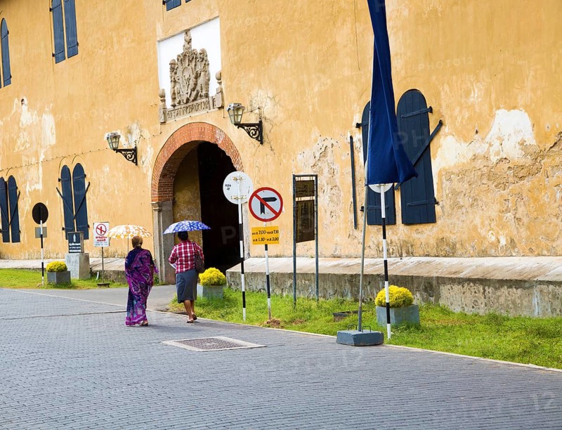 Women walking with umbrellas for shade towards the fort doorway exit in the historic town of Galle, Sri Lanka, Asia