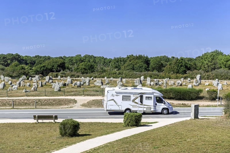 Motorhome, camper van driving past the Menec alignments, megalithic site among the Carnac standing stones, Morbihan, Brittany, France, Europe