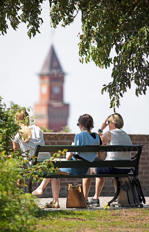 Swedish woman sitting on a park bench, behind them the tower of the town hall, Helsingborg, Skane laen, Sweden, Europe