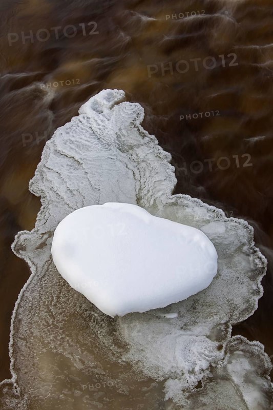 Heart-shaped snow patch on slush ice in river in winter
