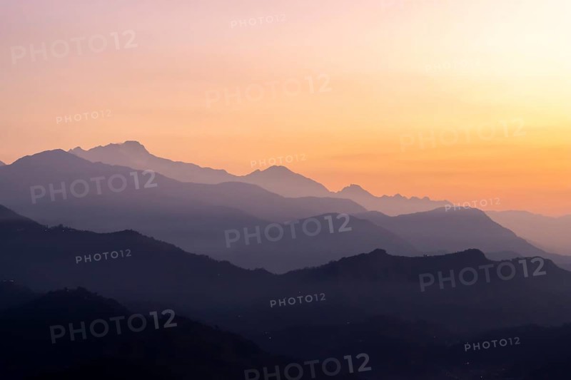 Silhouette of the Himalayan peaks, including Himalchuli and Baudha Himal, backlit by the orange sky, seen shortly before sunrise on a January, winter morning from Sarangkot, the popular viewpoint above Pokhara. Kaski District, Gandaki Province, Nepal, Asia