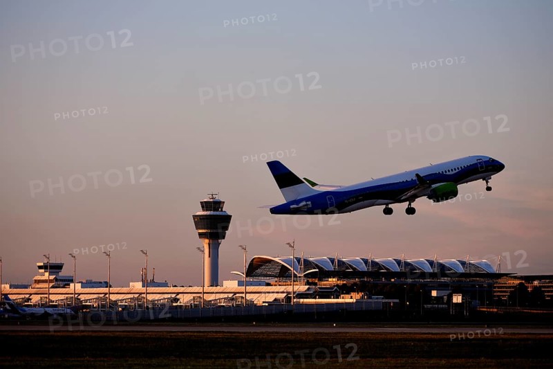 AirBaltic Airbus A220 taking off on Runway South with Terminal 1 and Tower in the sunset, Munich Airport, Upper Bavaria, Bavaria, Germany, Europe