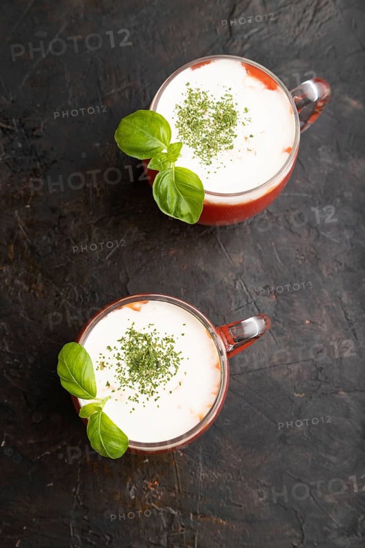 Tomato juice with basil and sour cream in glass on a black concrete background. Healthy drink concept. Top view, flat lay, close up