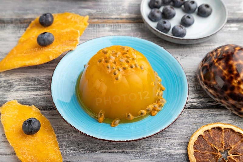 Mango and passion fruit jelly with blueberry on gray wooden background. side view, close up